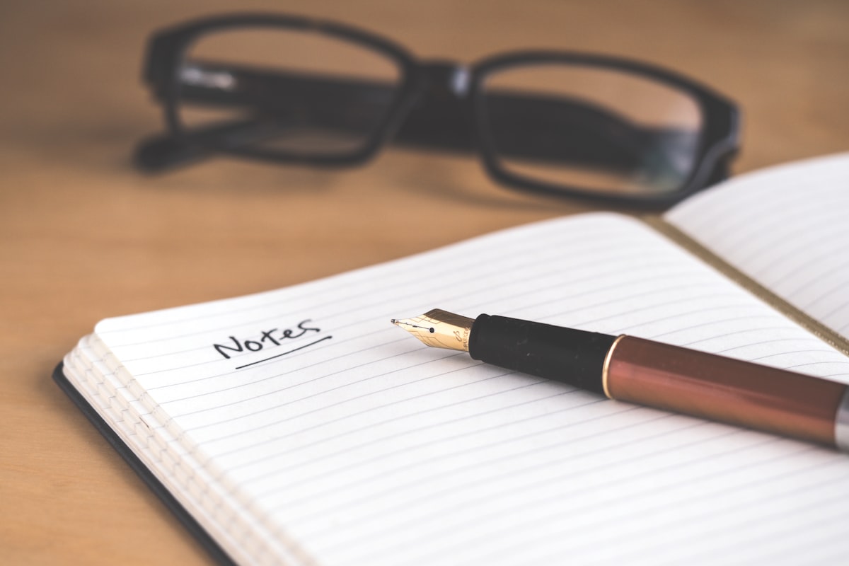 Open notebook with fountain pen and reading glasses